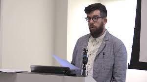 Bearded white man with glasses lecturing at a podium
